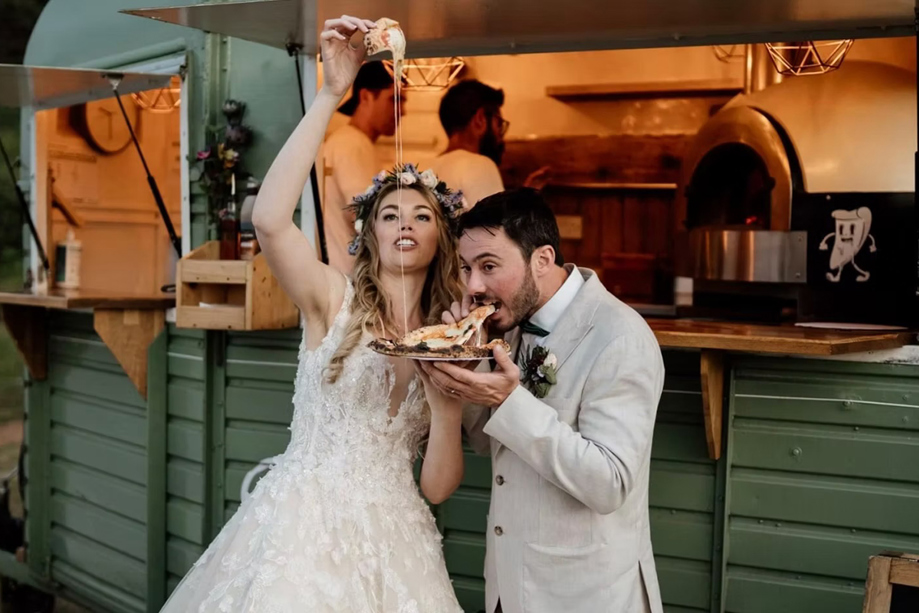 Bride and groom eating pizza in front of Dough Man's Land horsebox